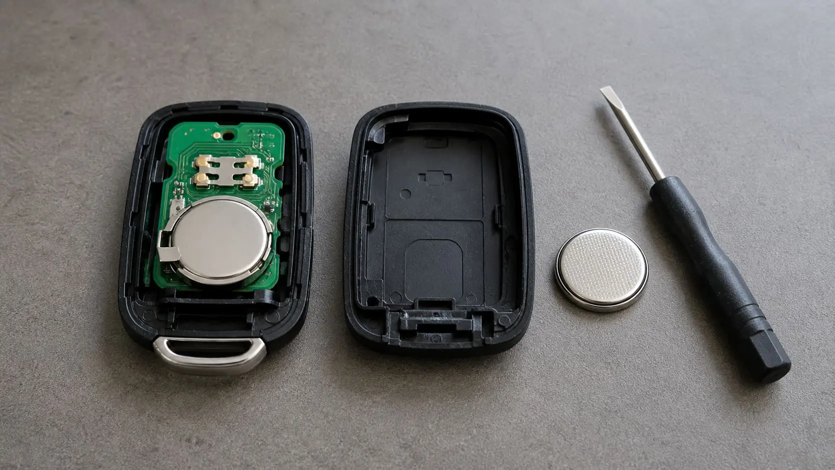 Opened generic car key fob with a coin-cell battery and small pry tool